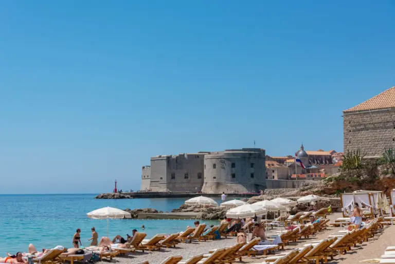 Sandy beach with loungers below the Dubrovnik city walls